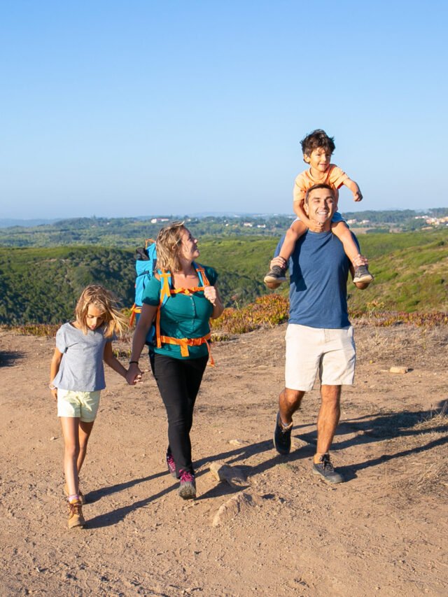 Happy family couple and children hiking in countryside