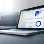 Profissional analisando gráficos de marketing digital em notebook para anunciar em portal de notícias