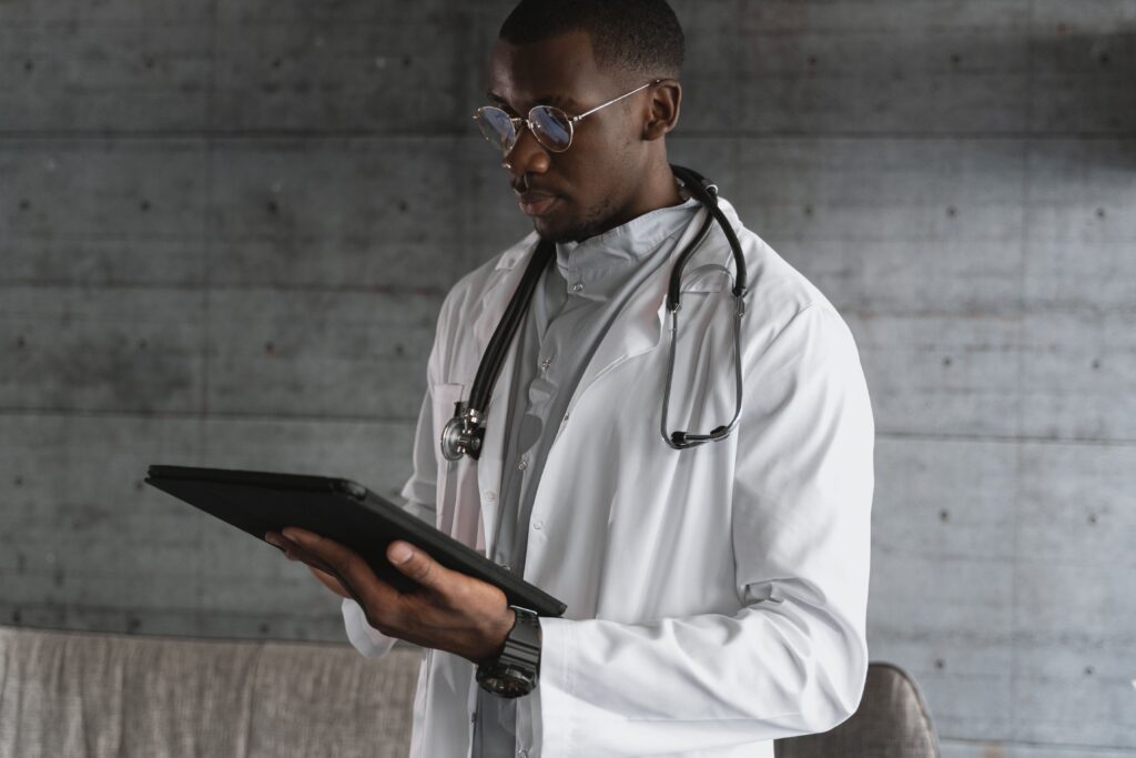 Medico de jaleco branco usando tablet em ambiente clinico
